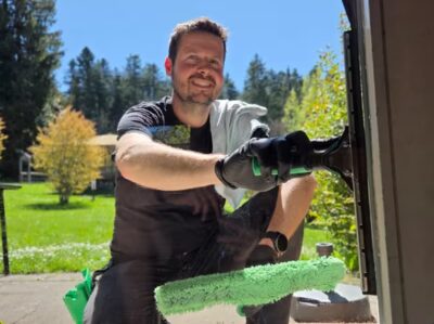 Mitarbeiter der Clean Lady reinigt ein Fenster mit Einwascher und Abzieher
