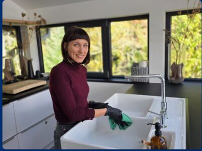 Mitarbeiterin der Clean Lady reinigt ein Spülbecken in einer Privatküche